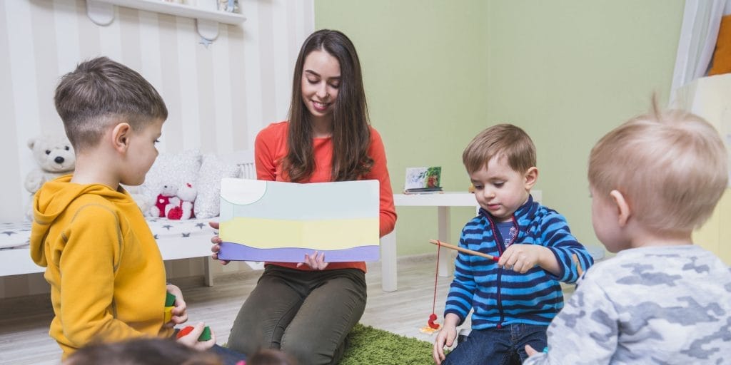 woman showing colored picture Kreşte Çalışmak İçin Kaç Saat Sertifika Olmalı, kreşte çalışmak, sertifika, çocuk eğitimleri, anaokulu uzaktan eğitimi, kreşte çalışmak için sertifika, kreşte çalışmak için belge