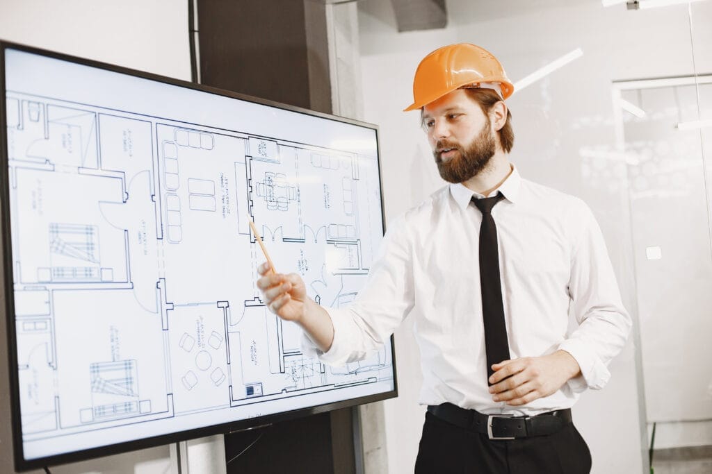 architect engineer man shows plan building tv screen Dekorasyon Sertifika Programları, Mimarlar İçin Sertifika Programları