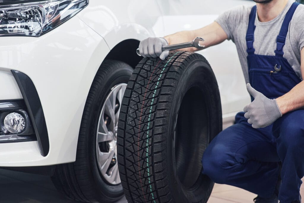 technician with blue workwear holding wrench tire while showing thumb up technician with blue workwear holding wrench tire while showing thumb up