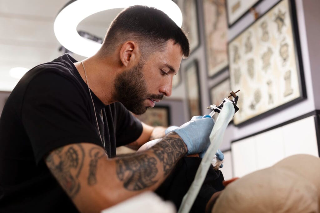 talented tattoo artist doing his job side view Dövme Ustalık Belgesi Nasıl Alınır?