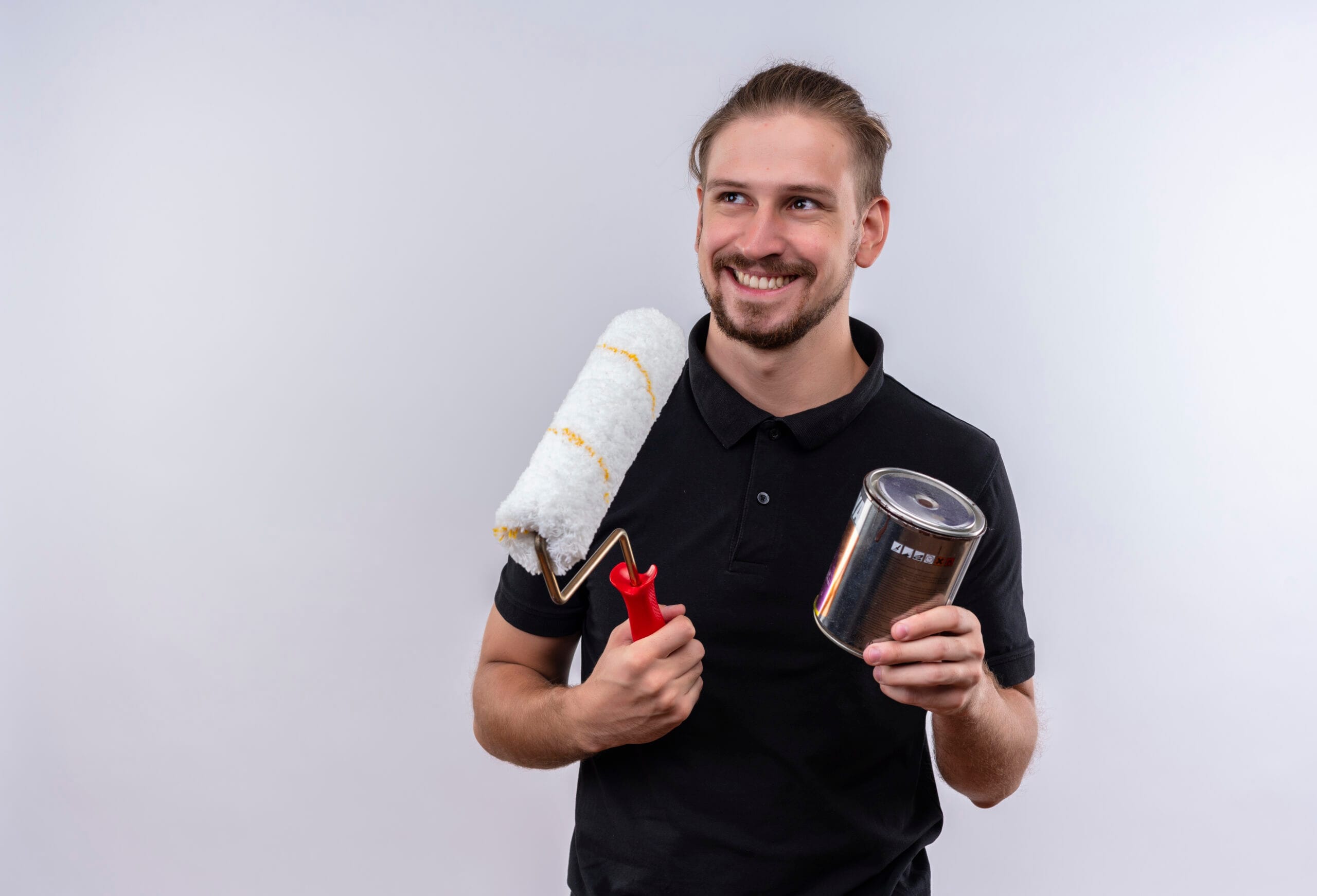 young handsome man black polo shirt holding paint roller paint can smiling cheerfully looking aside standing white background scaled Boyacı Ustalık Belgesi Nasıl Alınır?