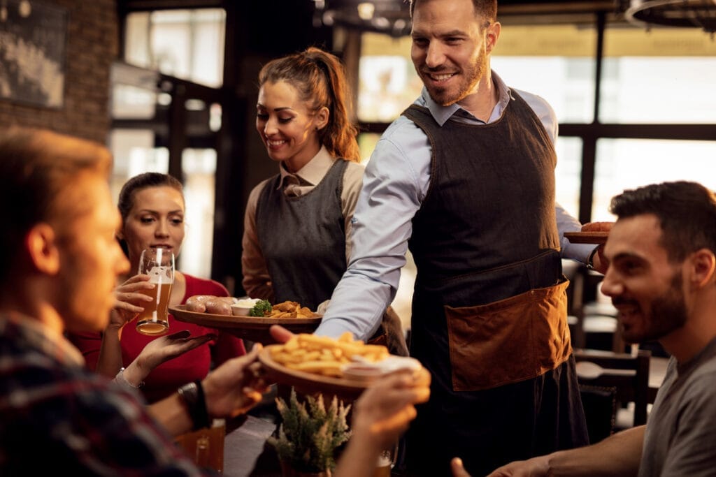 happy waiters bringing food table serving group friends restaurant Restoran Açmak İçin Gerekli Belgeler