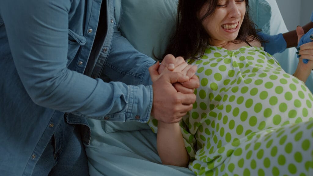 woman pain from childbirth holding hands with husband Doğum Koçluğu Eğitimi Ücretleri