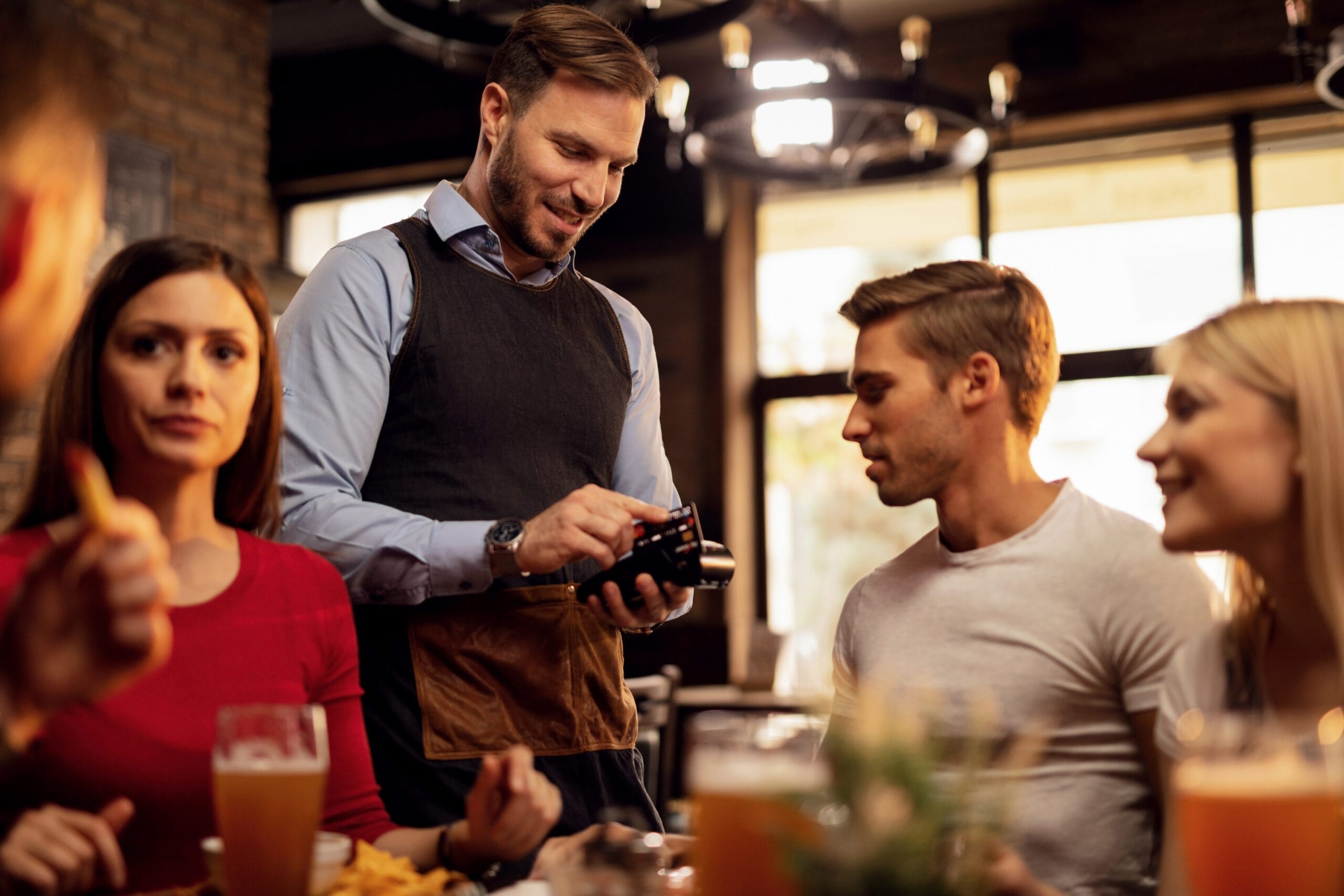 young waiter accepting credit card payment from his guest who is paying restaurant bill scaled Restoran Açmak İçin Gerekli Belgeler