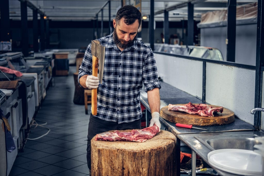 bearded butcher dressed fleece shirt cuts meat with bloody axe Kasaplık Ustalık Belgesi Nasıl Alınır?