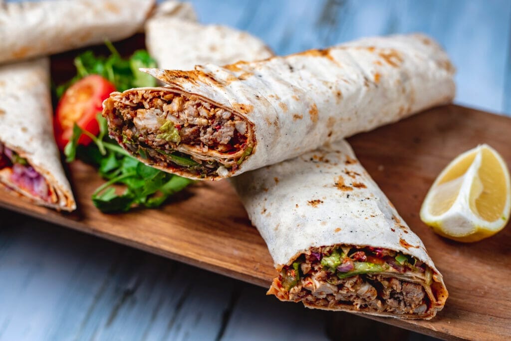 side view chicken doner with greens cucumber tomato sauce cucumber red onion pita slice lemon board Dönerci Ustalık Belgesi Nereden Alınır?