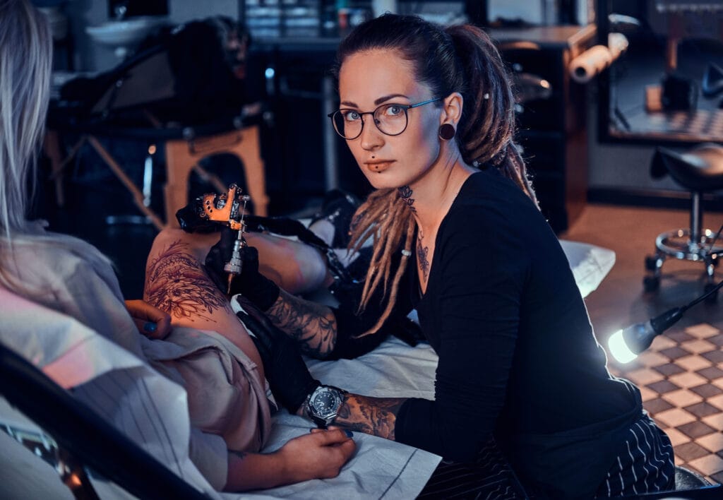 beautiful creative master with dreadlocks is working new peace big leg tattoo customer Dövme Ustalık Sertifikası Nereden Alınır