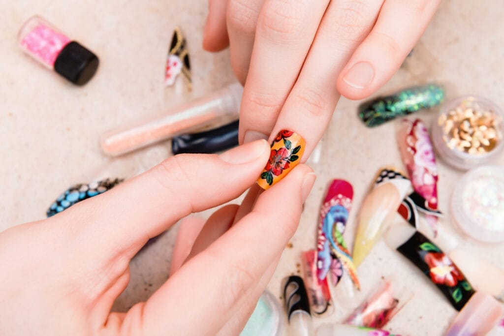 girl trying artificial nails tips with flower nail design 1 Protez Tırnak Sertifikası Nasıl Alınır
