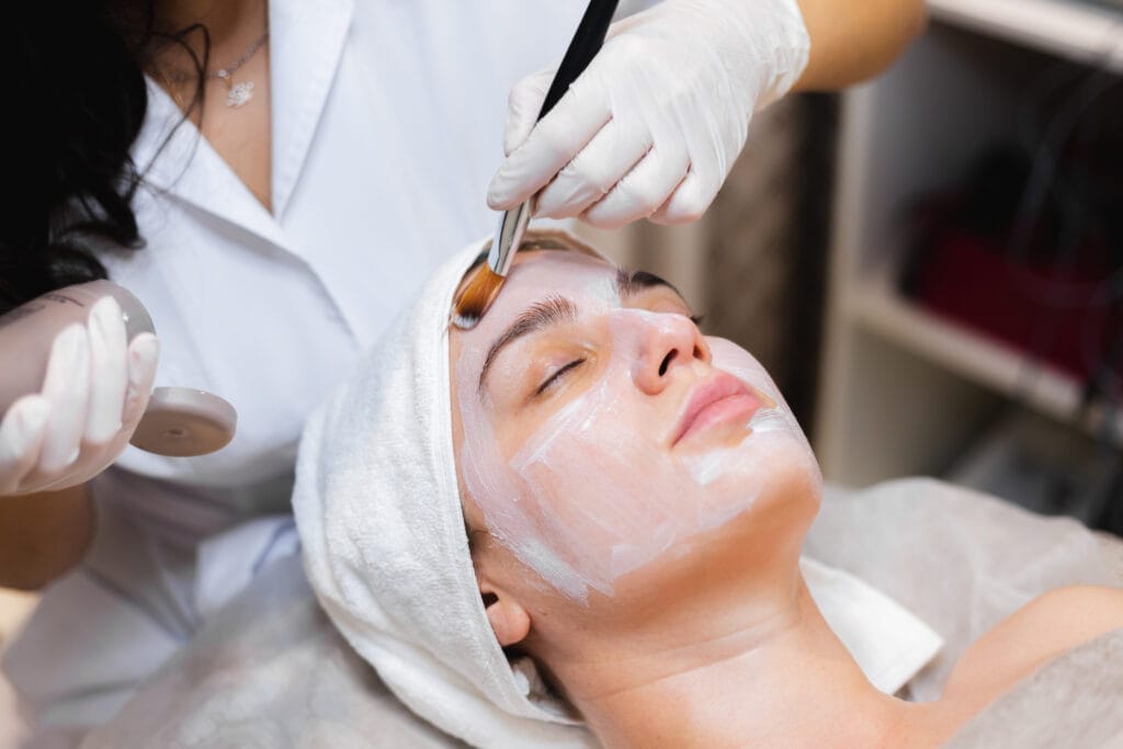beautician with brush applies white moisturizing mask face young girl client spa beauty salon Güzellik Merkezi Açmak İçin Alınabilecek Sertifikalar ve Kurslar