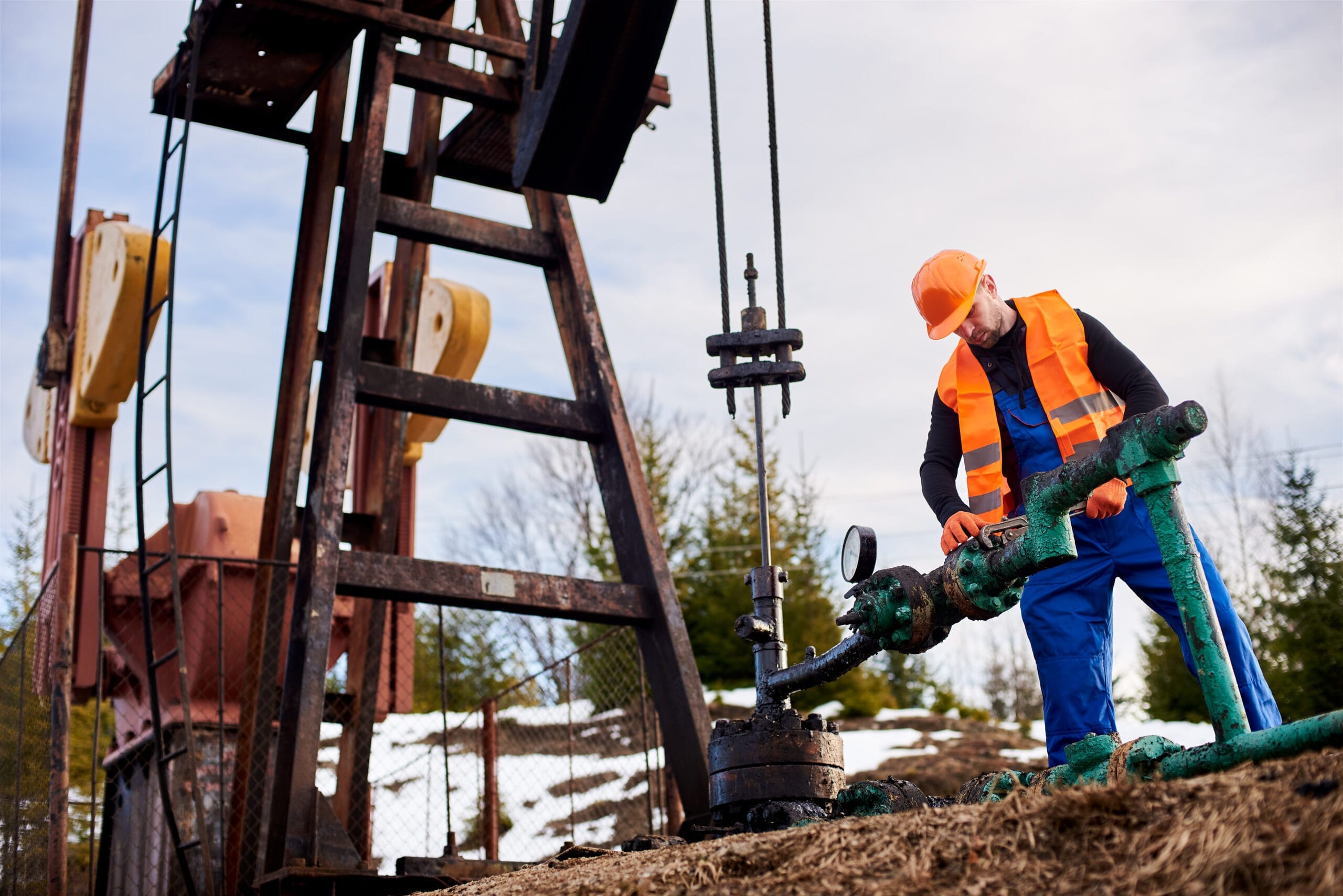 oil worker orange uniform helmet working with pipe wrench near oil pump jack scaled Zemin Delgi Operatörlük Belgesi