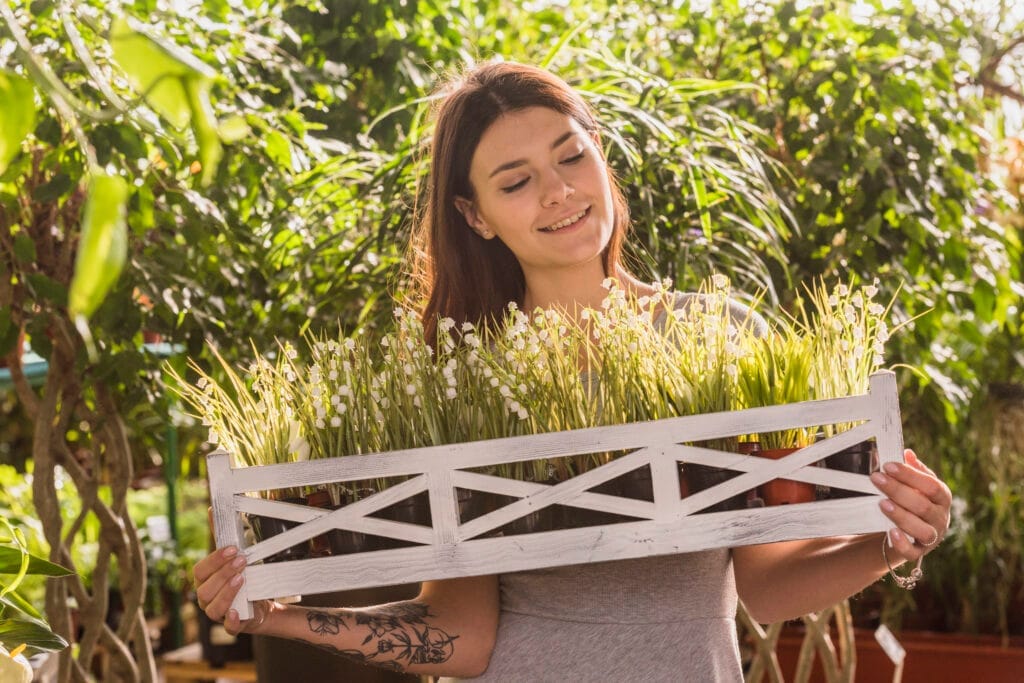 attractive happy woman holding wooden shelf with plants Tıbbi ve Aromatik Bitki Yetiştiriciliği Sertifikası Nasıl Alınır?