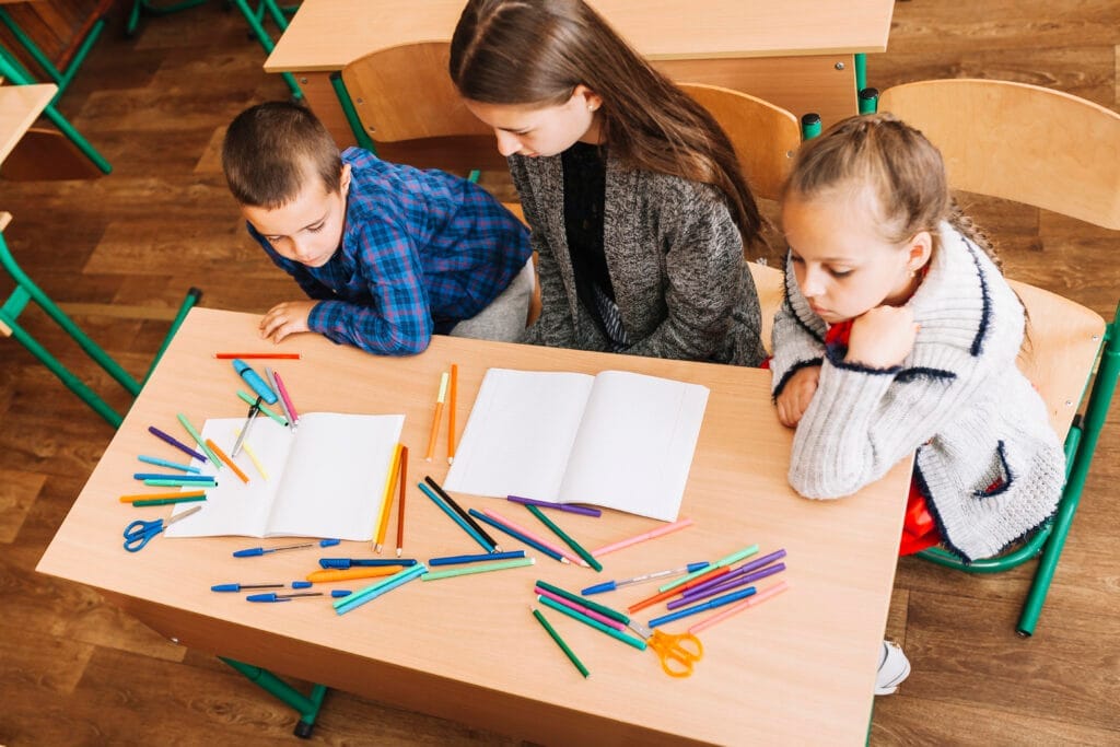 teacher sitting pupils Okul Öncesi Sertifikası Nasıl Alınır?