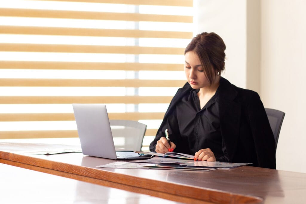 front view young beautiful businesswoman black shirt black jacket using her silver laptop writing reading working inside her office work job building Hukuk ve Adli Sekreterlik Sertifikası