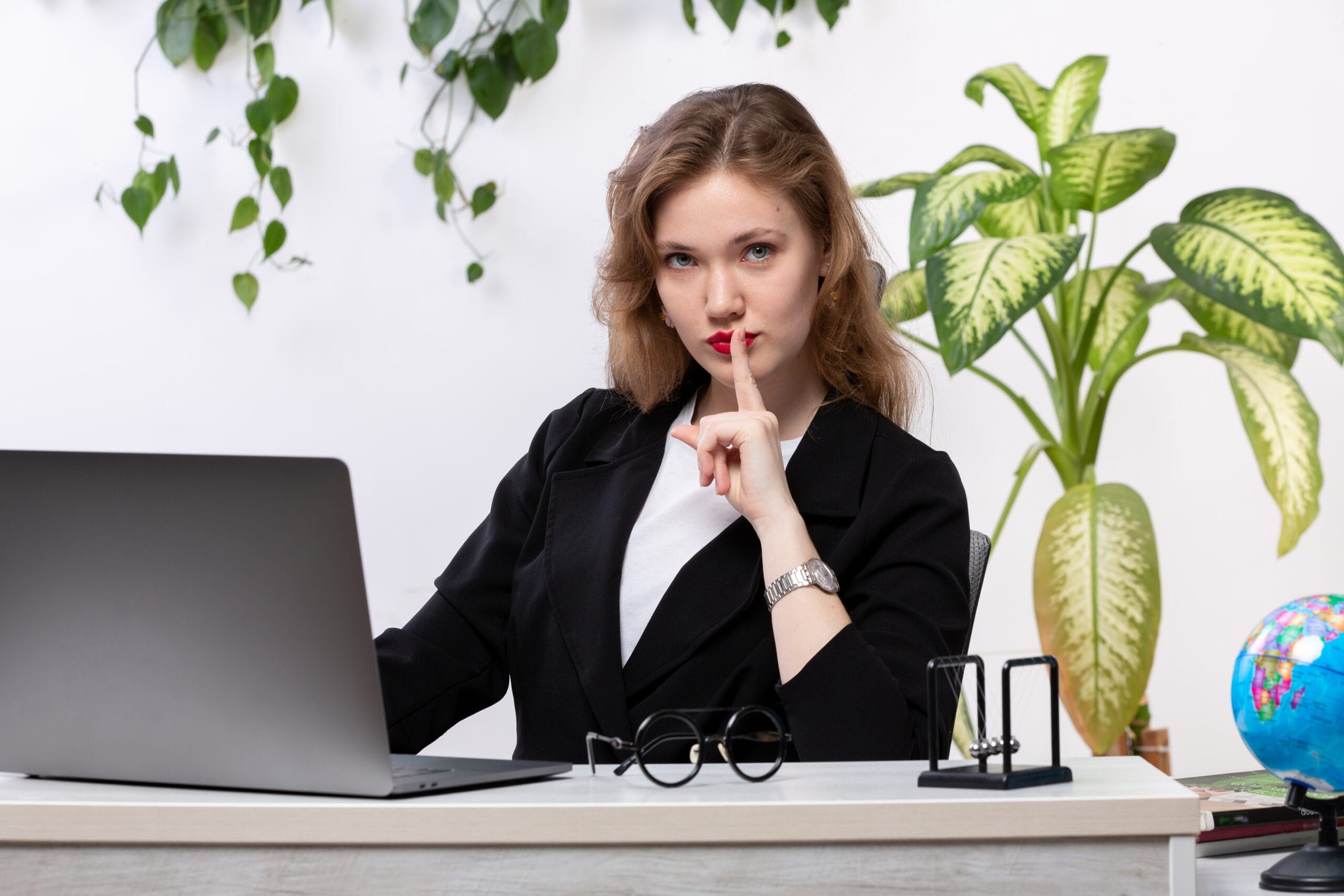 front view young beautiful lady white shirt black jacket using her laptop front table smiling showing silence sign with leaves hanging scaled Hukuk ve Adli Sekreterlik Sertifikası
