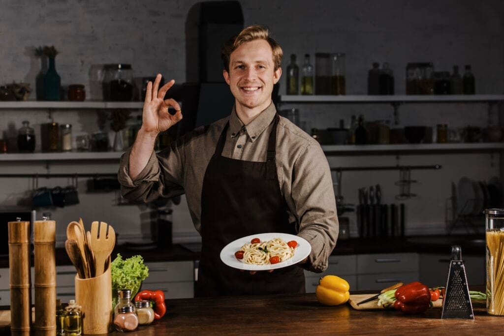 mid shot chef holding plate with pasta making ok sign Aşçılık Belgesi Nasıl Alınır