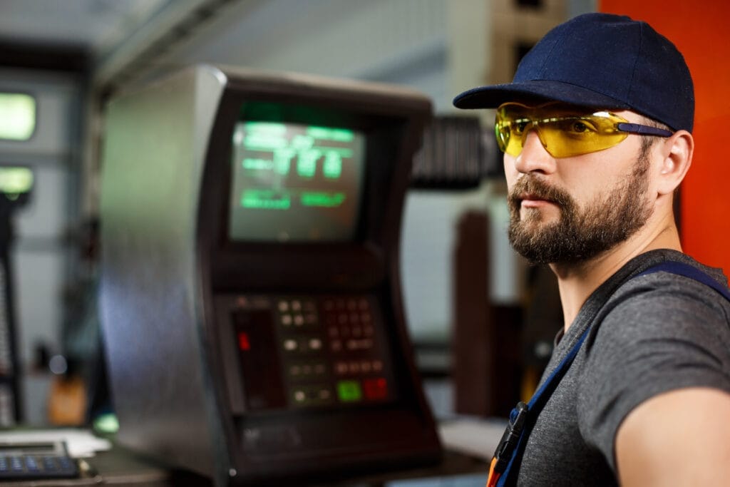 portrait worker onalls near computer steel factory background CNC Operatörü Nasıl Olunur?